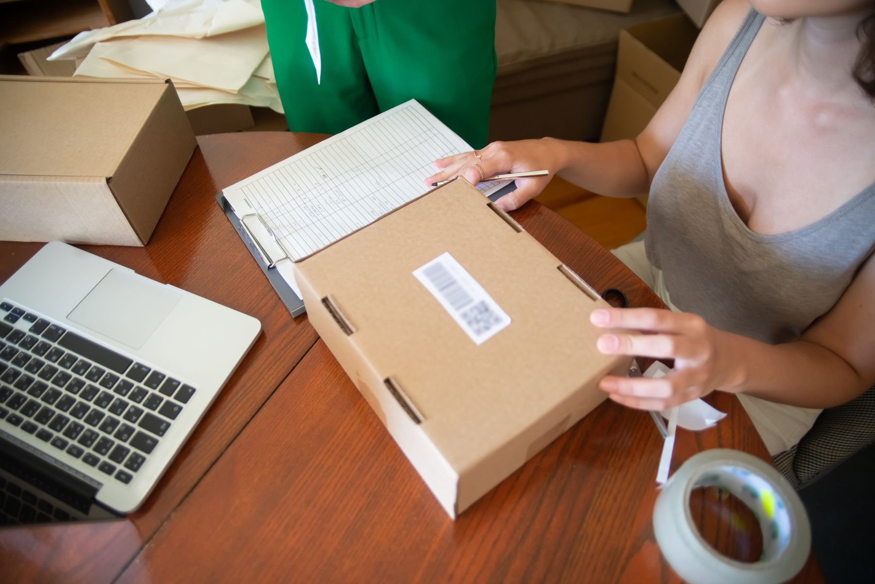 Seller preparing a labeled parcel beside a laptop